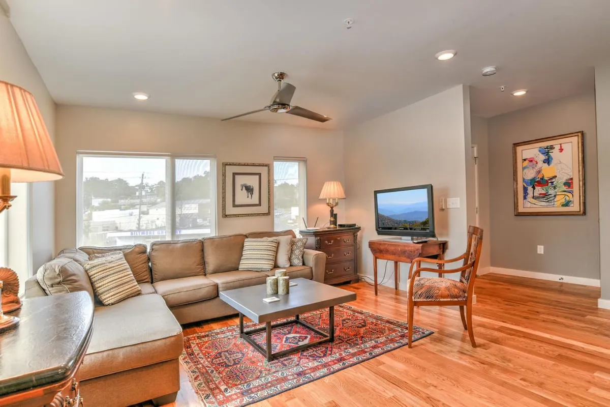A cozy and comfortable living room featuring a plush sofa, chic coffee table, decorative artwork, and a large TV—all set in an environment perfect for relaxing or entertaining.