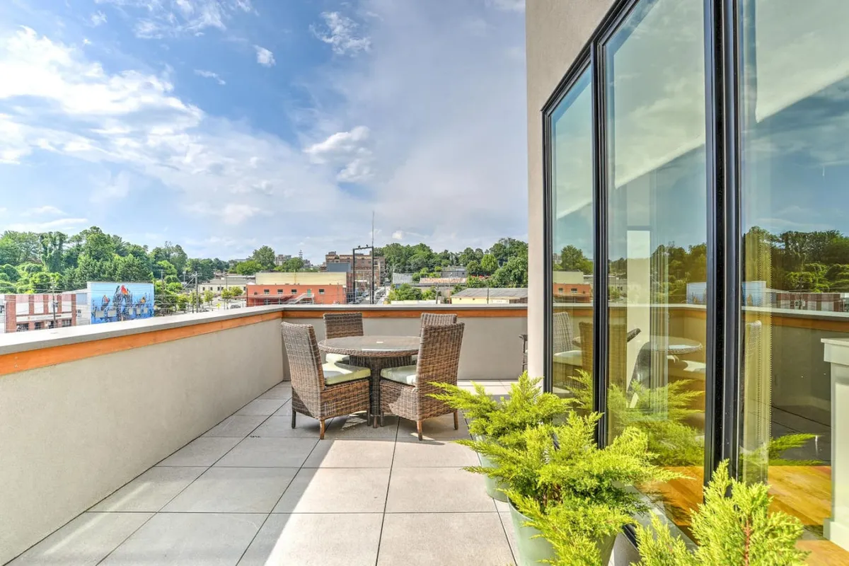 This image captures a private rooftop terrace set with a stylish outdoor dining set surrounded by lush green ferns. The panoramic city view stretches beyond the terrace, creating a serene yet dynamic urban backdrop. The space is perfectly arranged for outdoor dining, relaxation, or hosting social gatherings, embodying the elevated, exclusive feel described in the section.