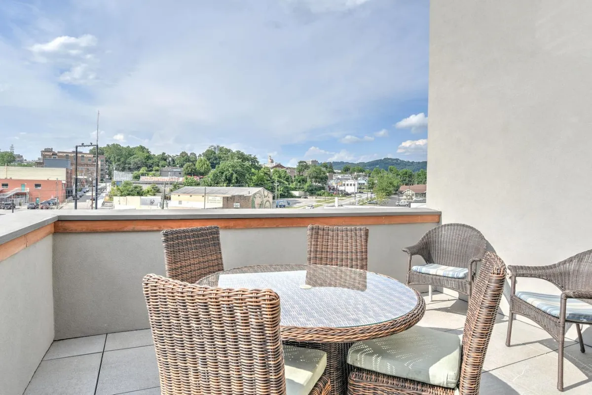 The image shows an inviting rooftop setup featuring wicker furniture and a glass table, set against a backdrop of the town’s rooftops and sky. The scene suggests informal gatherings, fresh air dining, and a casual, relaxed vibe—ideal for both quiet moments and small get-togethers.