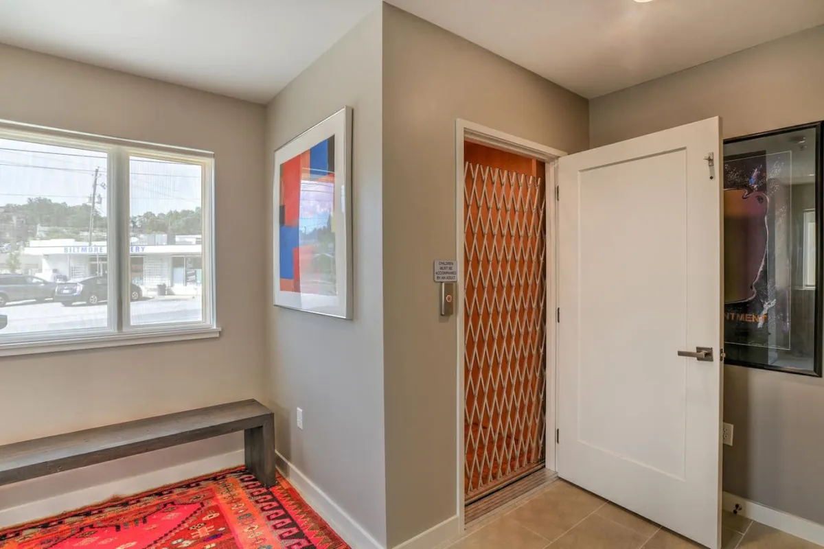 A stylish hallway with colorful artwork, a sleek bench, and an elevator door, creating a welcoming and modern first impression while highlighting ease of access.